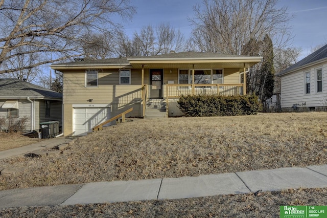 bungalow-style home featuring a garage, covered porch, and central air condition unit