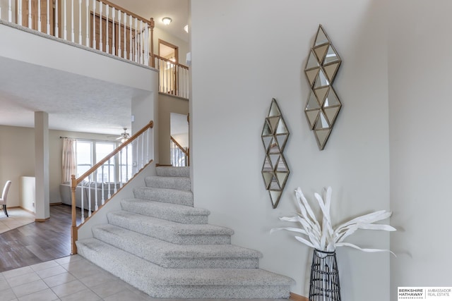 stairs with tile patterned floors and a high ceiling