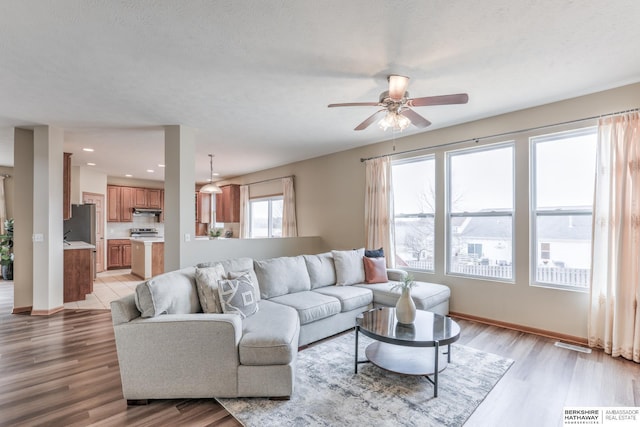 living room with ceiling fan, light hardwood / wood-style flooring, and a textured ceiling