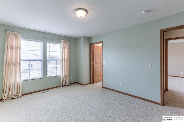 spare room with light carpet and a textured ceiling