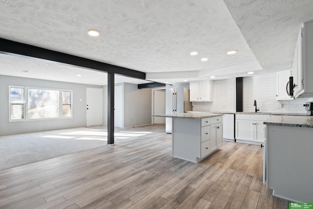 kitchen featuring a kitchen island, white cabinets, and light stone counters