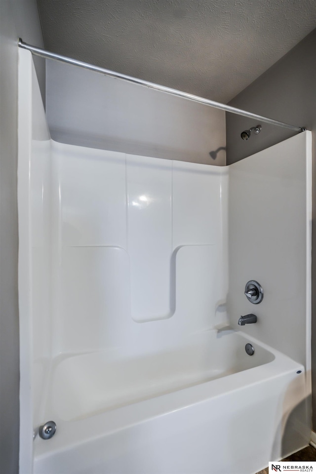 bathroom featuring shower / bathing tub combination and a textured ceiling