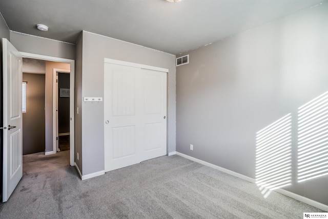 unfurnished bedroom featuring light carpet and a closet