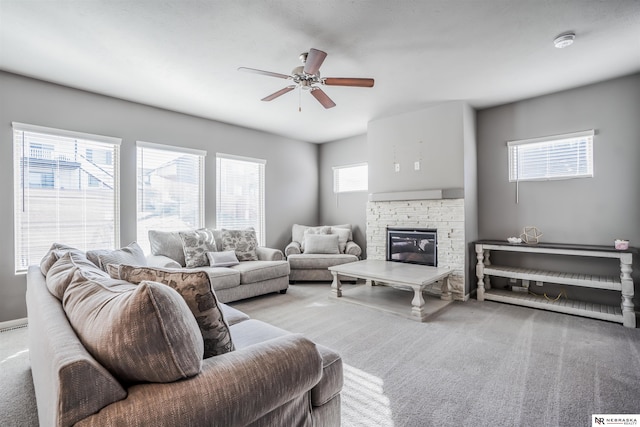 carpeted living room with ceiling fan and a fireplace