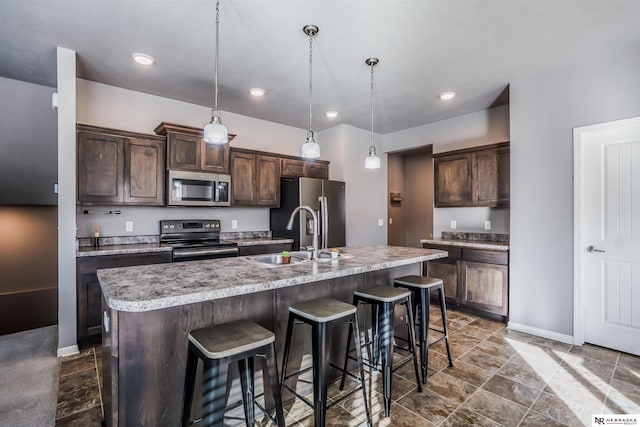 kitchen with a kitchen island with sink, sink, stainless steel appliances, and dark brown cabinetry