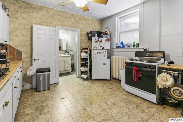 kitchen with radiator, white cabinets, white fridge, ceiling fan, and gas range