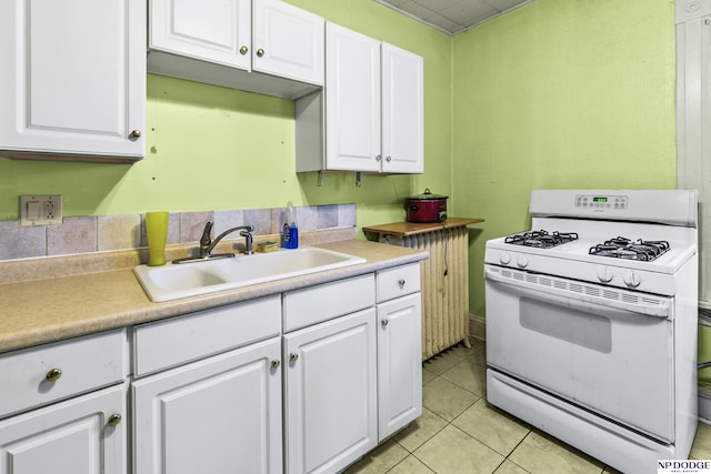 kitchen featuring sink, white gas stove, and white cabinets