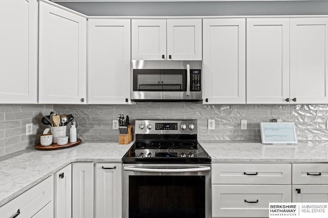 kitchen featuring backsplash, light stone countertops, white cabinets, and appliances with stainless steel finishes