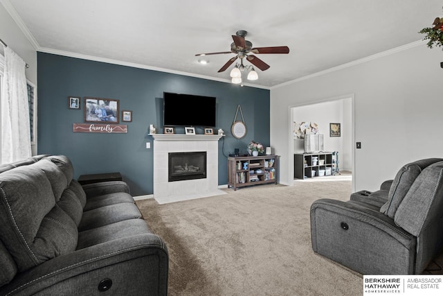 carpeted living room with a tiled fireplace, ornamental molding, and ceiling fan