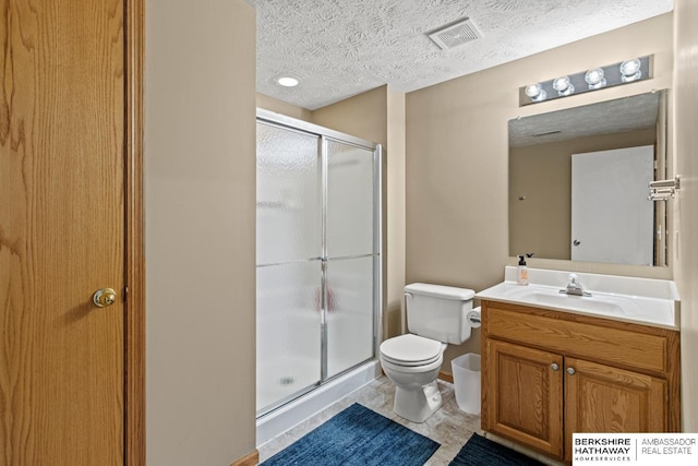 bathroom with a shower with door, vanity, a textured ceiling, and toilet