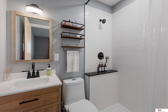 bathroom with tiled shower, vanity, and toilet