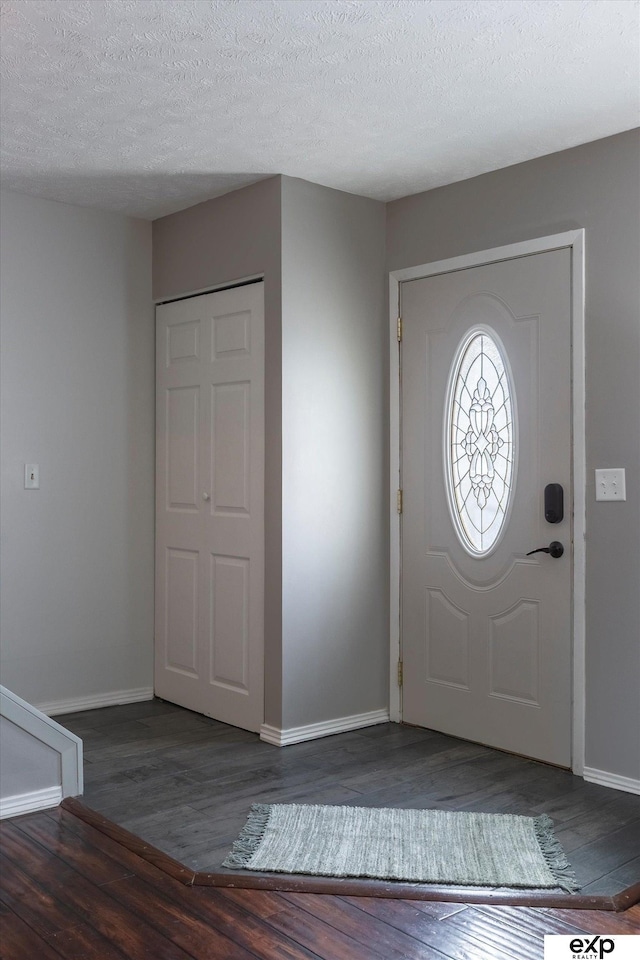 foyer entrance with dark hardwood / wood-style floors and a textured ceiling