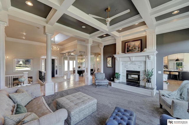 tiled living room with beamed ceiling, coffered ceiling, decorative columns, and a tile fireplace