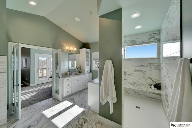 bathroom with lofted ceiling, vanity, and a tile shower