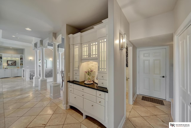 hallway with ornate columns and light tile patterned floors