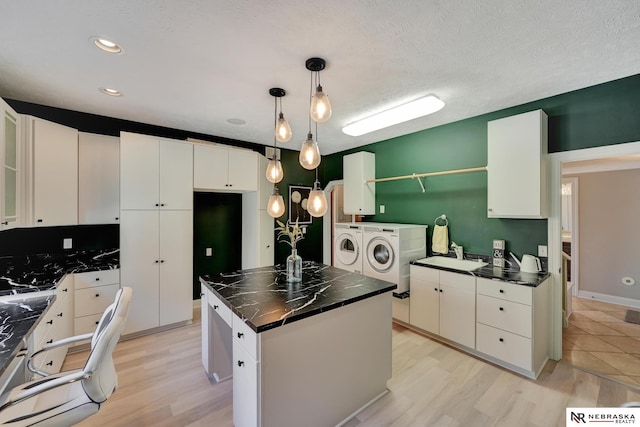 kitchen with white cabinetry, washing machine and clothes dryer, hanging light fixtures, and a kitchen island