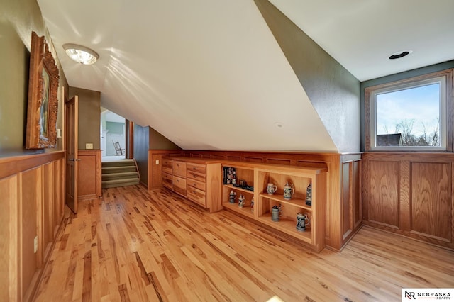 additional living space with lofted ceiling, wooden walls, and light hardwood / wood-style floors