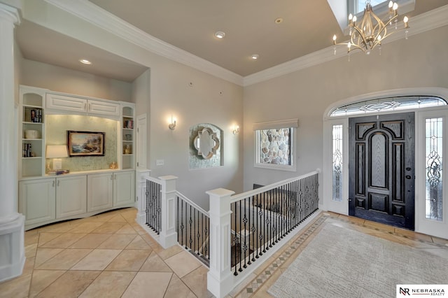 tiled entryway with ornamental molding, decorative columns, and a notable chandelier