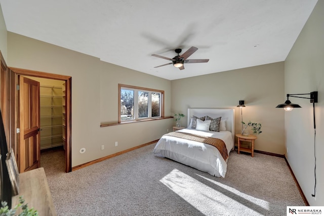 carpeted bedroom featuring a walk in closet and ceiling fan