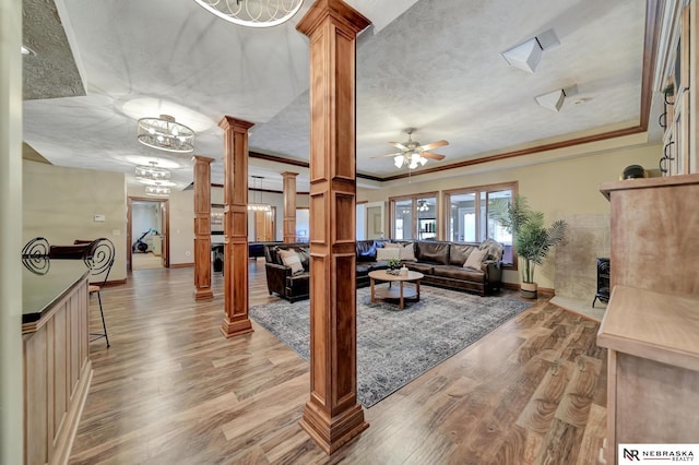 living room featuring ornate columns, crown molding, ceiling fan, and light wood-type flooring