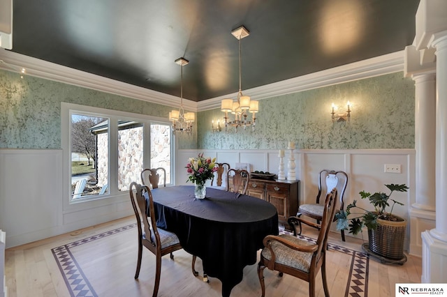 dining room featuring decorative columns, crown molding, a chandelier, and light hardwood / wood-style floors