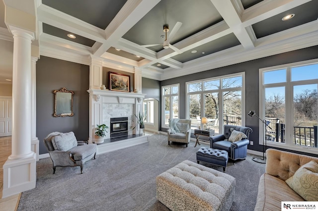 carpeted living room with beamed ceiling, a large fireplace, coffered ceiling, and ornate columns