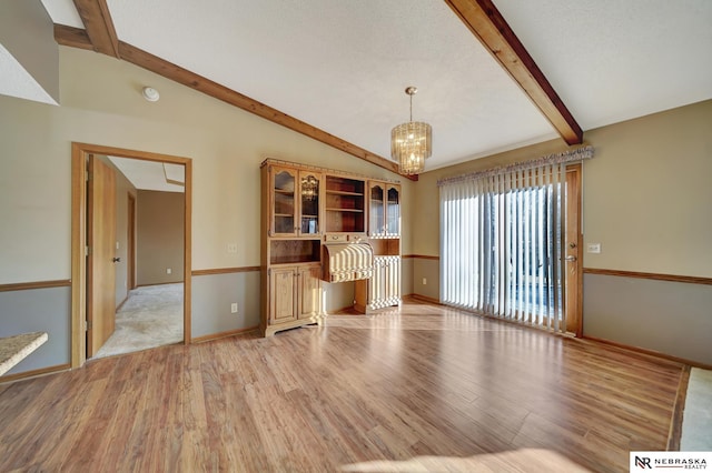 unfurnished living room featuring a chandelier, lofted ceiling with beams, and light hardwood / wood-style flooring