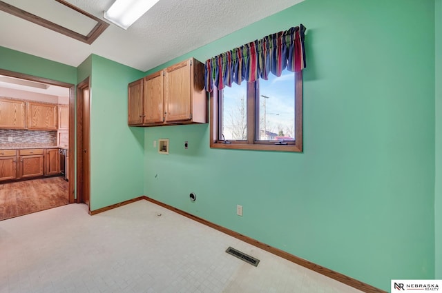 laundry room with cabinets, hookup for a washing machine, a textured ceiling, and electric dryer hookup