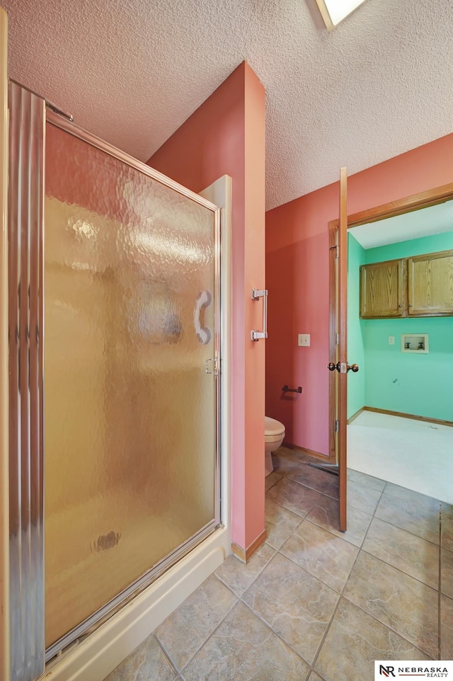 bathroom featuring a shower with door, a textured ceiling, and toilet