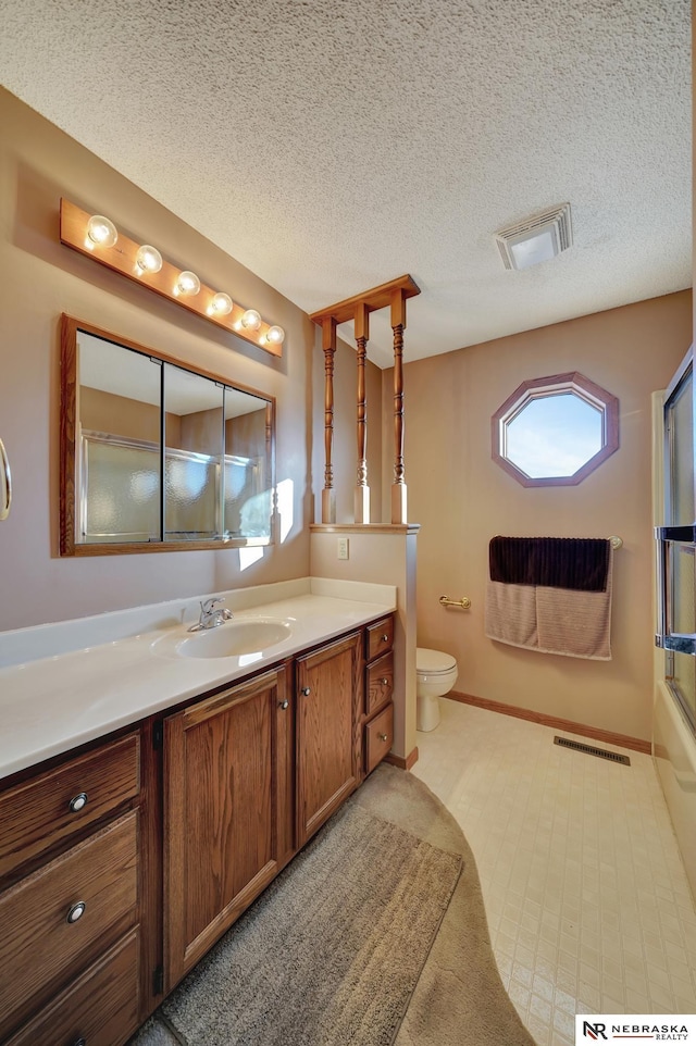 full bathroom with vanity, a textured ceiling, shower / bath combination with glass door, and toilet