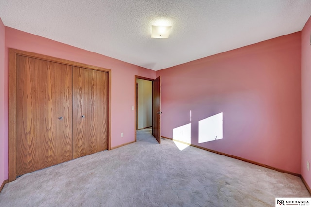 unfurnished bedroom featuring light colored carpet, a textured ceiling, and a closet