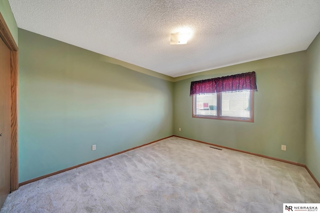 unfurnished room featuring light carpet and a textured ceiling