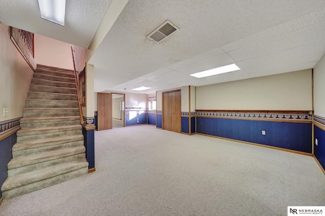 basement featuring a drop ceiling and carpet floors