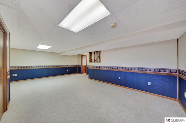 basement with a paneled ceiling and carpet flooring