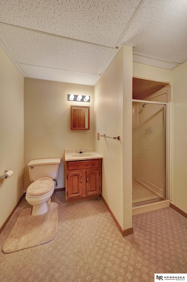 bathroom with a shower with door, vanity, a paneled ceiling, and toilet