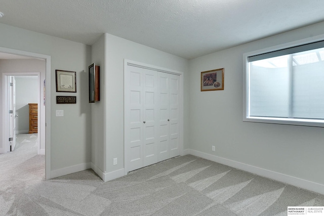 unfurnished bedroom featuring a closet, light carpet, and a textured ceiling