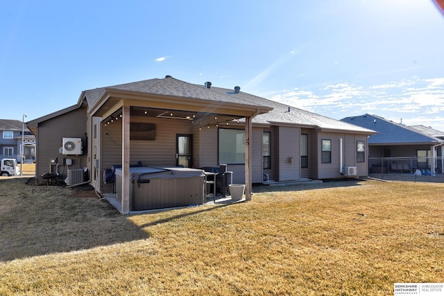 rear view of property with cooling unit, a yard, and a hot tub