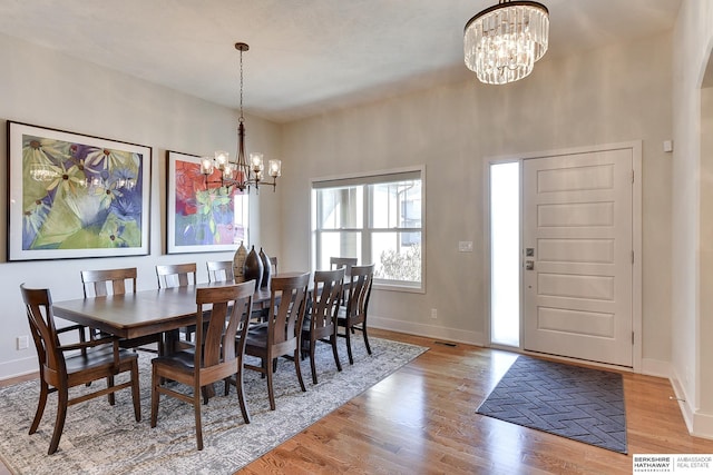 dining space featuring light wood-type flooring and an inviting chandelier