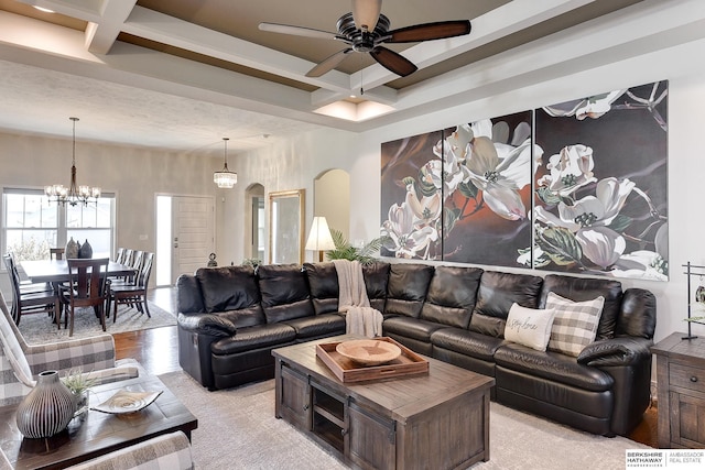 living room featuring beamed ceiling, coffered ceiling, and ceiling fan with notable chandelier