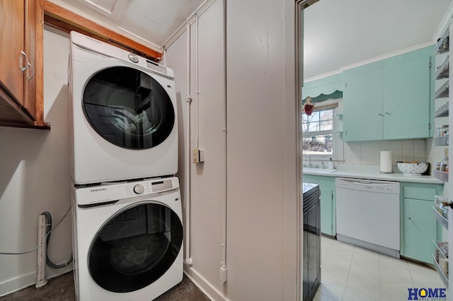 washroom with stacked washer / drying machine and sink