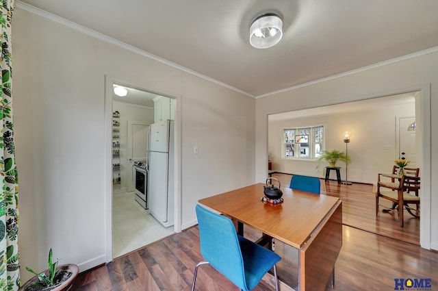 dining space with ornamental molding and light hardwood / wood-style floors