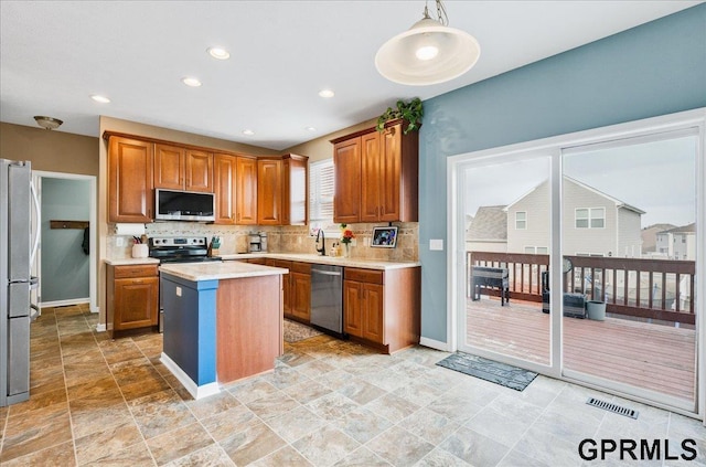 kitchen featuring sink, tasteful backsplash, appliances with stainless steel finishes, a kitchen island, and pendant lighting