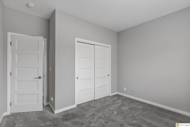 unfurnished bedroom with dark colored carpet and a closet