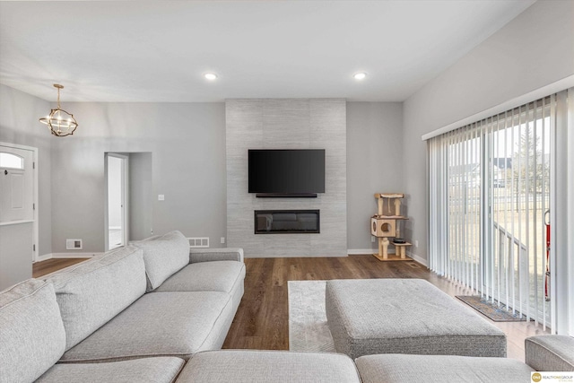 living room featuring a large fireplace, wood-type flooring, and a chandelier