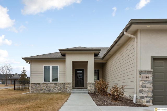 property entrance featuring a garage and a lawn