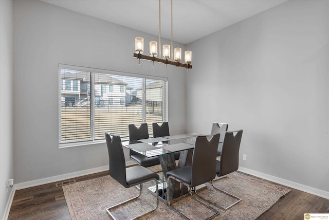 dining area with dark hardwood / wood-style flooring and a chandelier