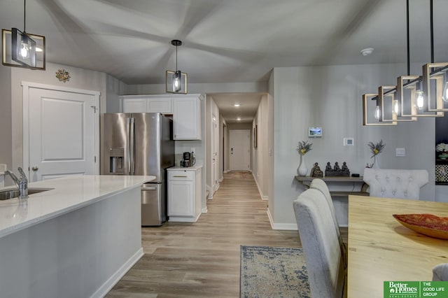 kitchen with white cabinetry, stainless steel refrigerator with ice dispenser, and decorative light fixtures