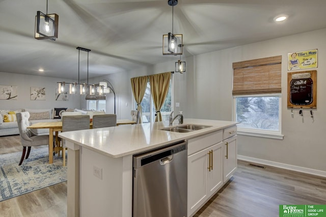 kitchen with sink, stainless steel dishwasher, an island with sink, and white cabinets