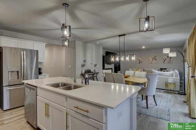 kitchen featuring sink, an island with sink, pendant lighting, stainless steel appliances, and white cabinets