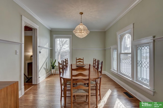 dining space featuring light hardwood / wood-style flooring, ornamental molding, and a chandelier